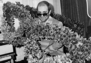 Fotografia English Singer Elton John at his Arrival in Paris Bunch of Flowers in The Shape of Glasses He Wears December 1St 1976